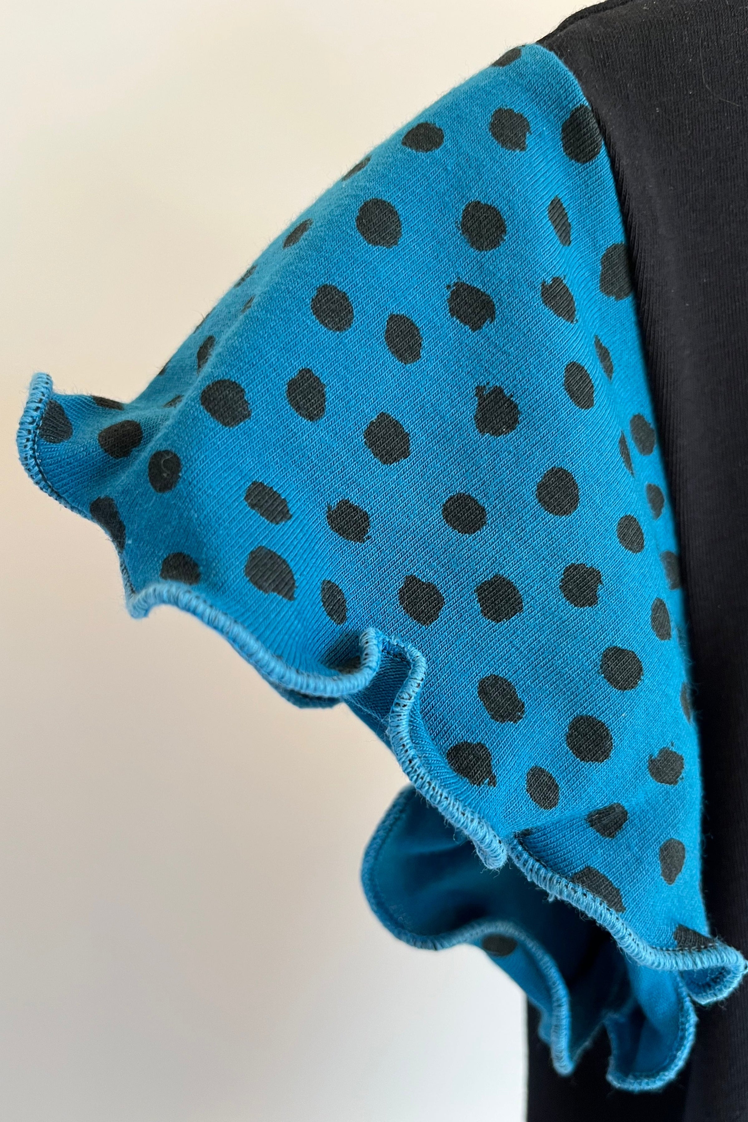 Blue fabric with black polka dots on a white background