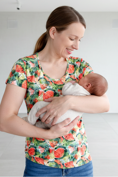 Woman holding a baby in an empty room with large windows