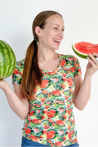 Woman holding a whole watermelon and a slice of watermelon against a white background