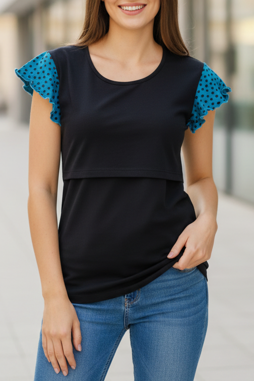 Woman wearing a black top with blue ruffled sleeves and blue jeans standing in an urban setting.