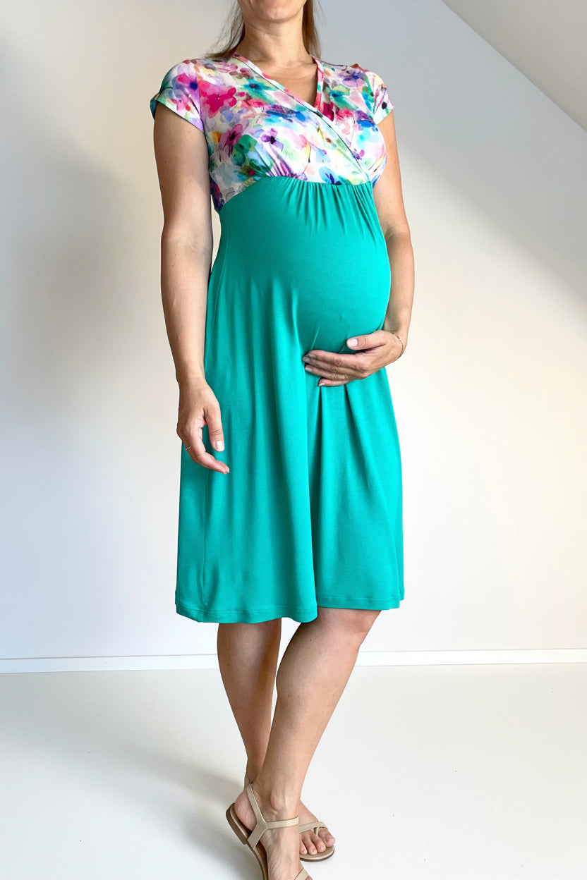 Woman wearing a teal maternity dress with a colorful floral top.
