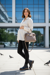 A pregnant woman wearing black opaque maternity tights and black boots, standing against a white background.