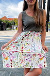 Woman holding a floral-patterned maternity dress on a street.
