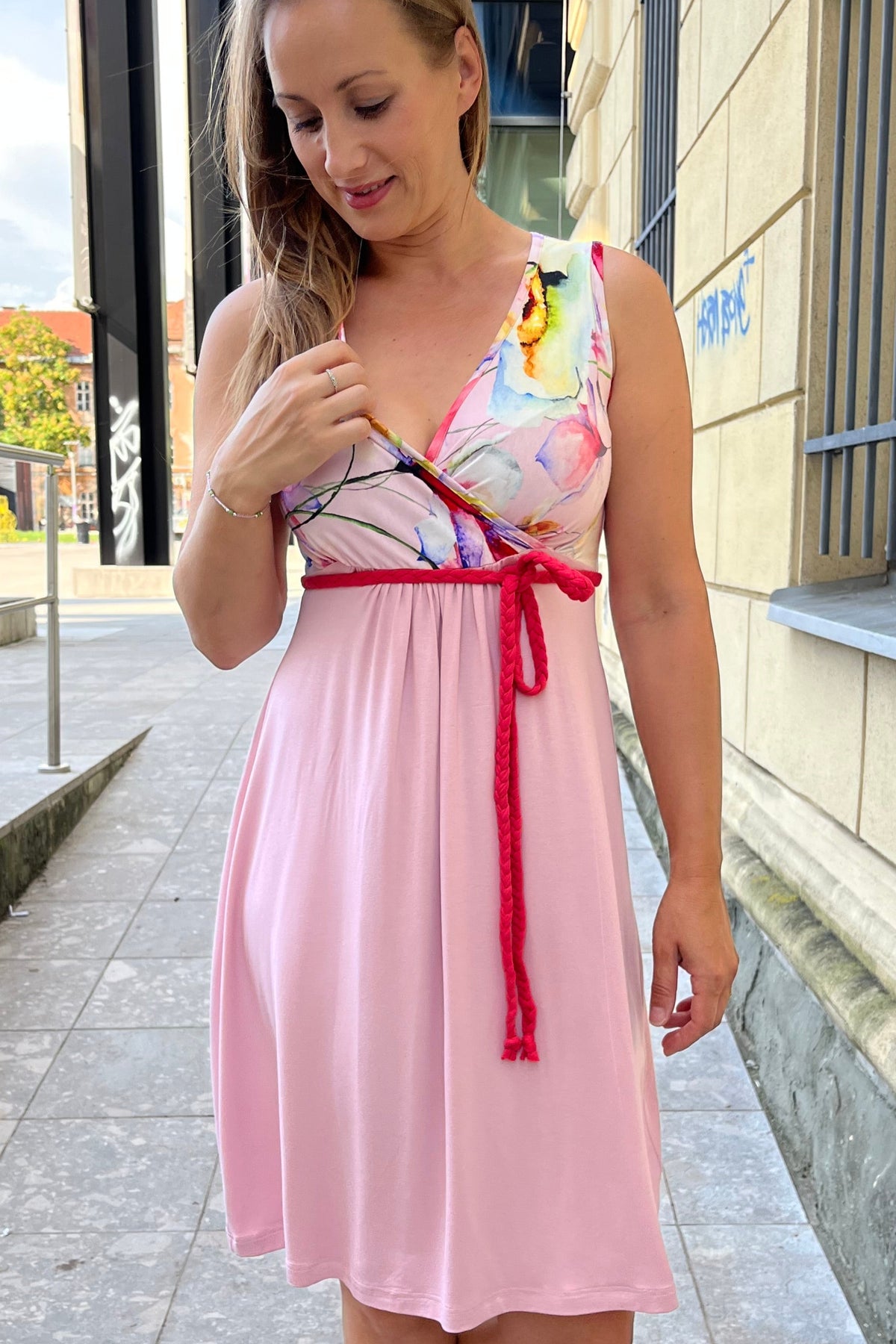 Woman in a pink maternity dress standing on a tiled floor