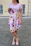 Woman in a colorful brestfeeding dress standing on a pavement with a building in the background