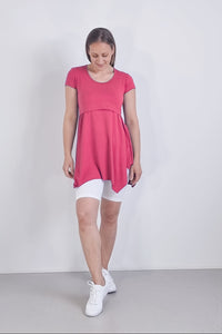 Woman wearing a pink dress with white shorts against a plain background